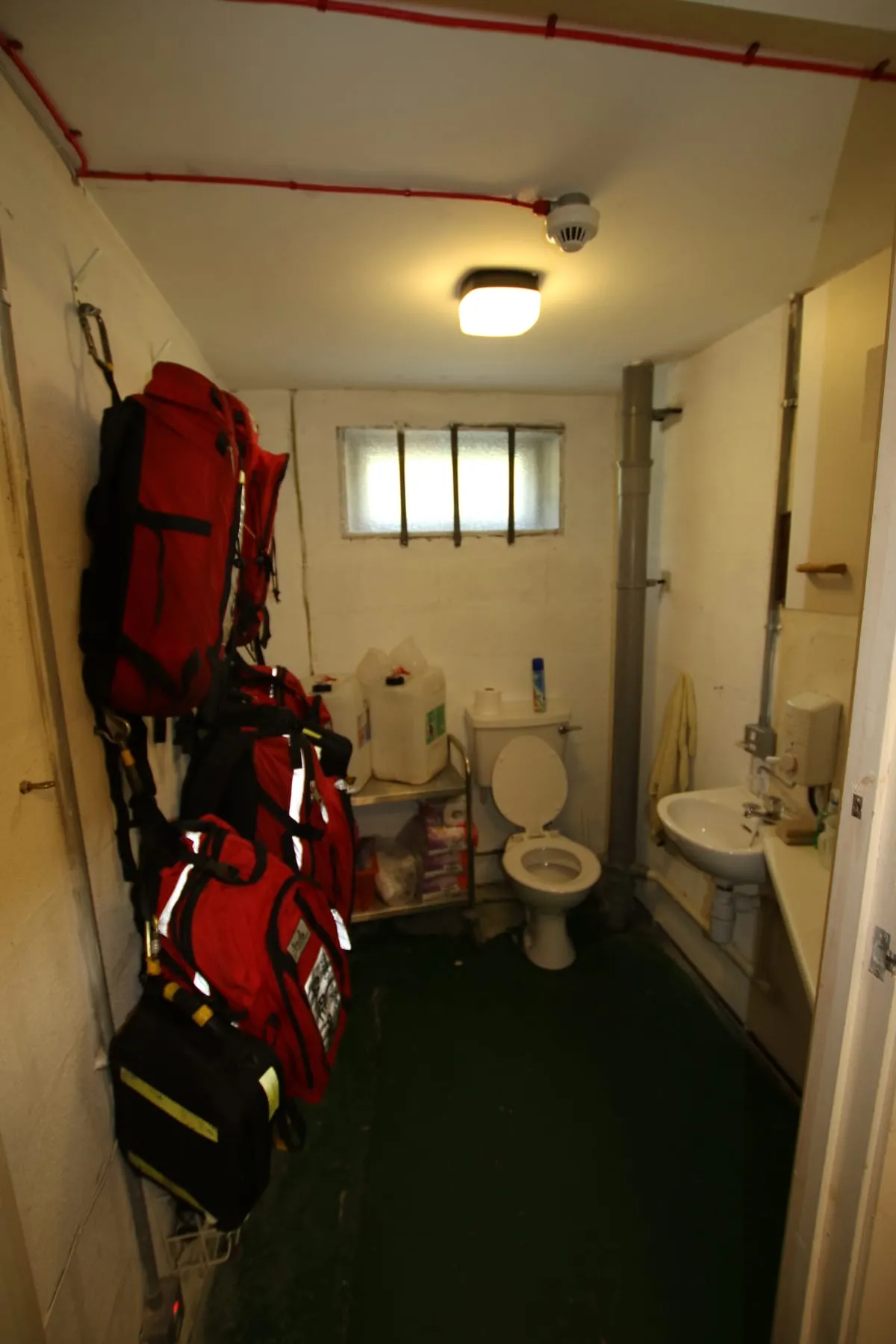Rescue kit hanging beside a toilet and sink in a narrow room