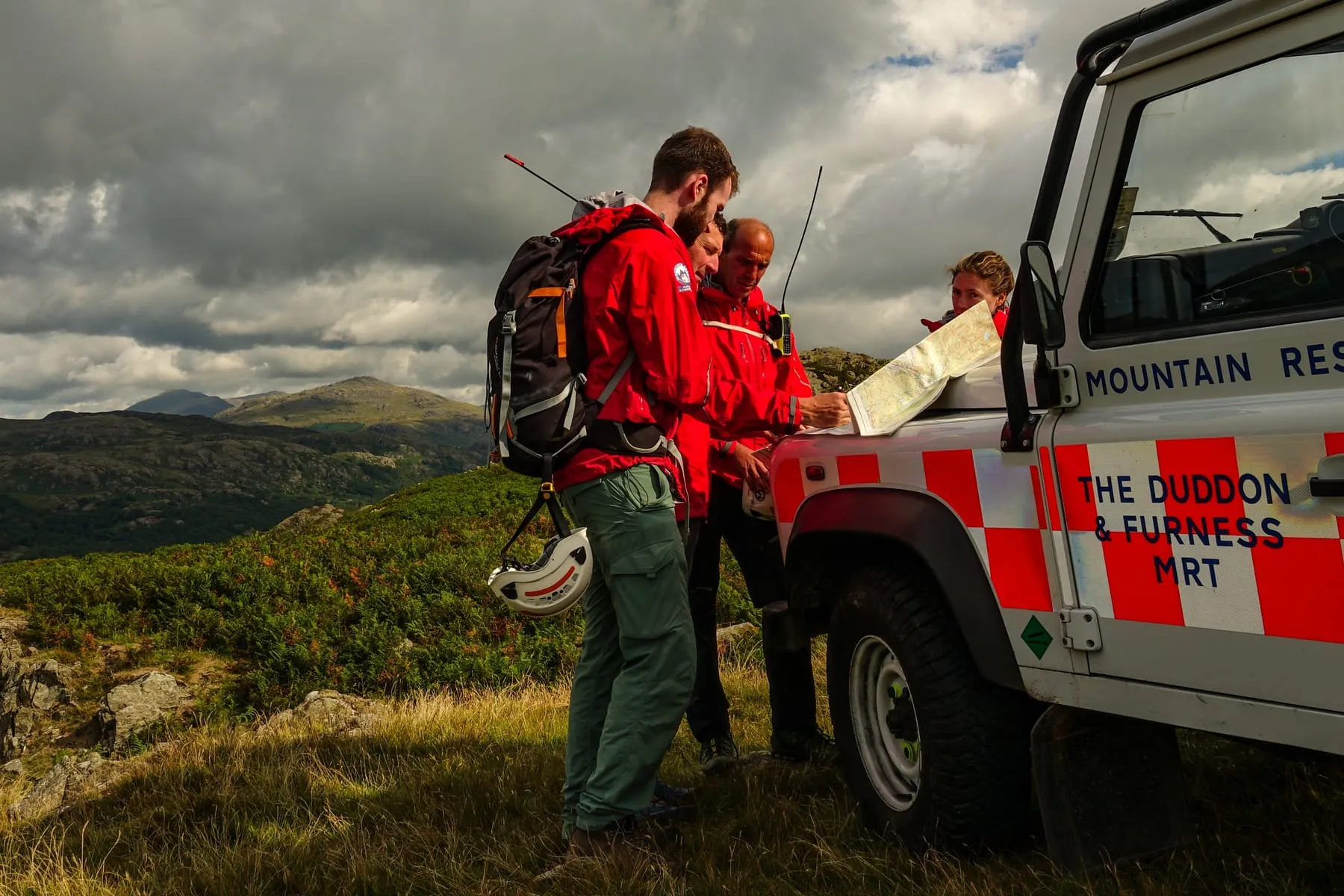 Team members reading a map on the bonnet of a Land Rover