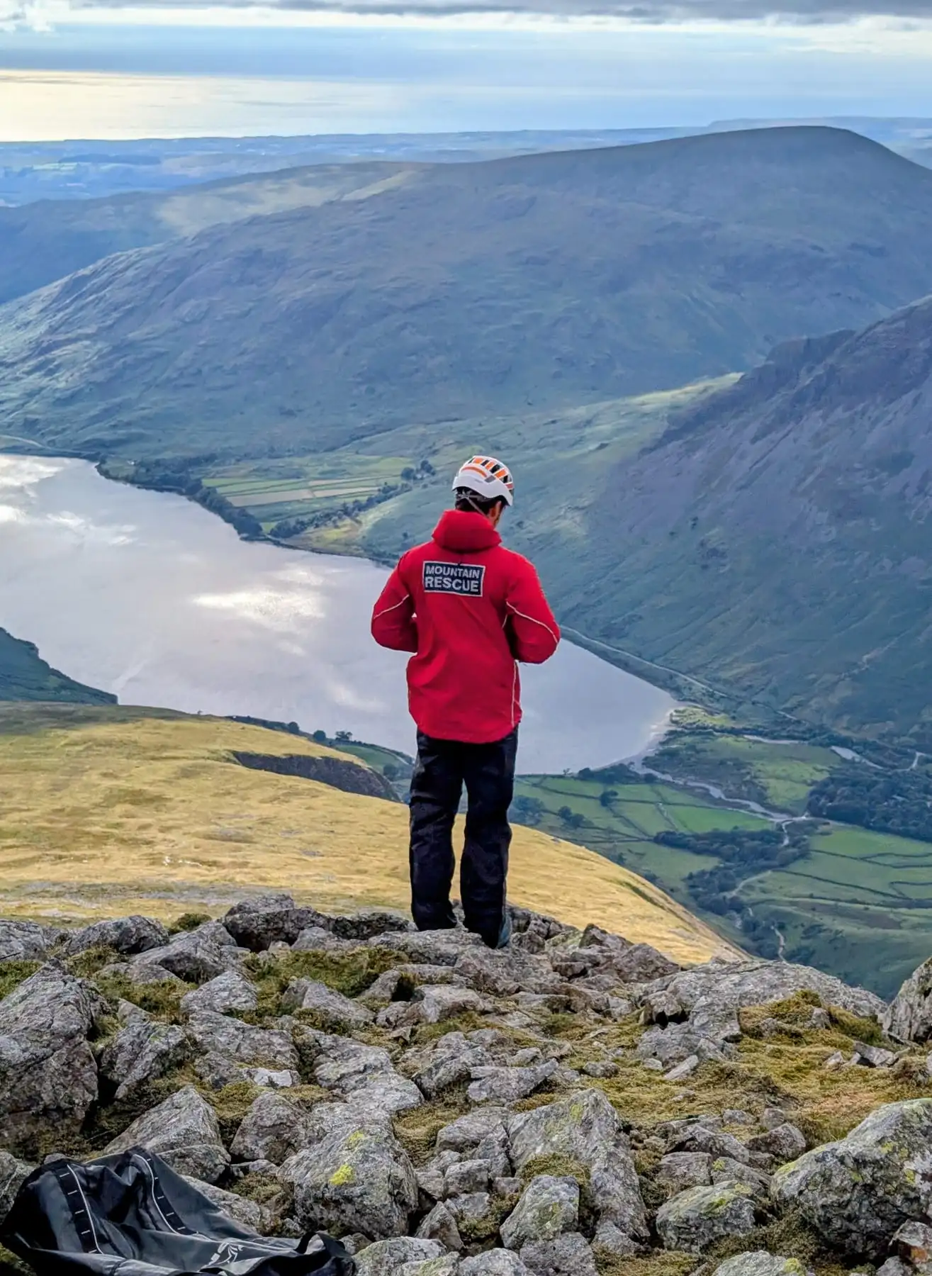 A team member looking out over a lake from a rocky summit