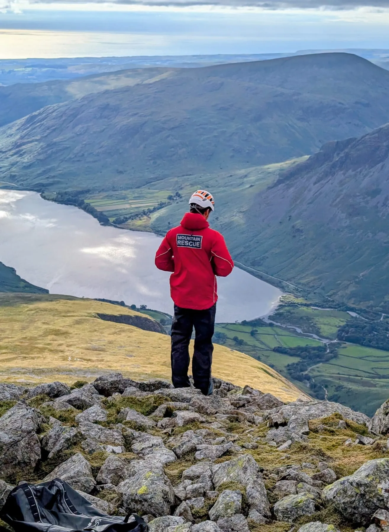 A team member looking out over a lake from a rocky summit