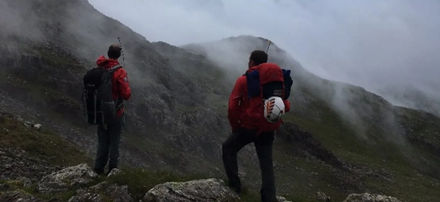 Two team members on a misty ridge