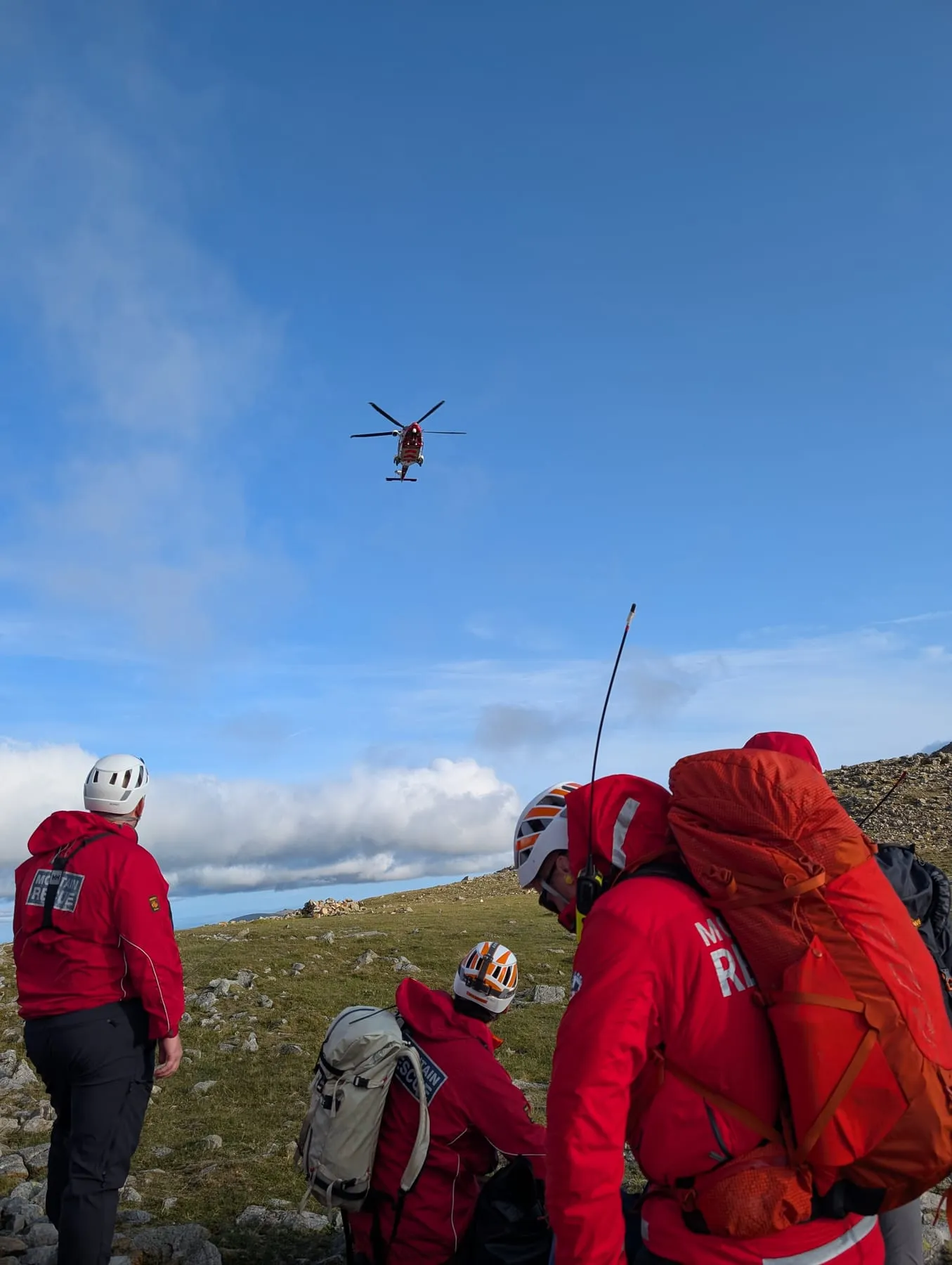Team members with radios watching a helicopter approach