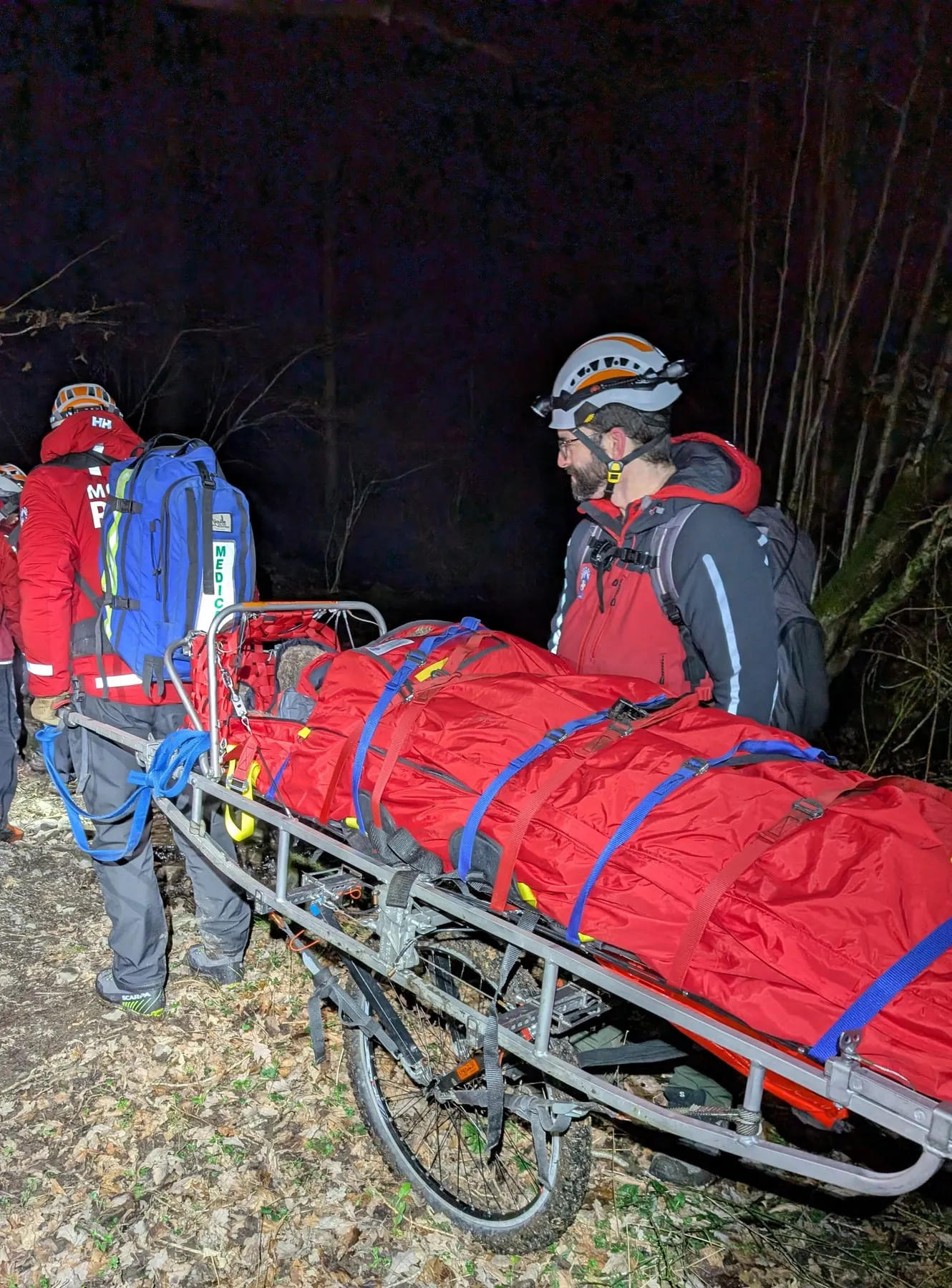Team members with a wheeled stretcher at night