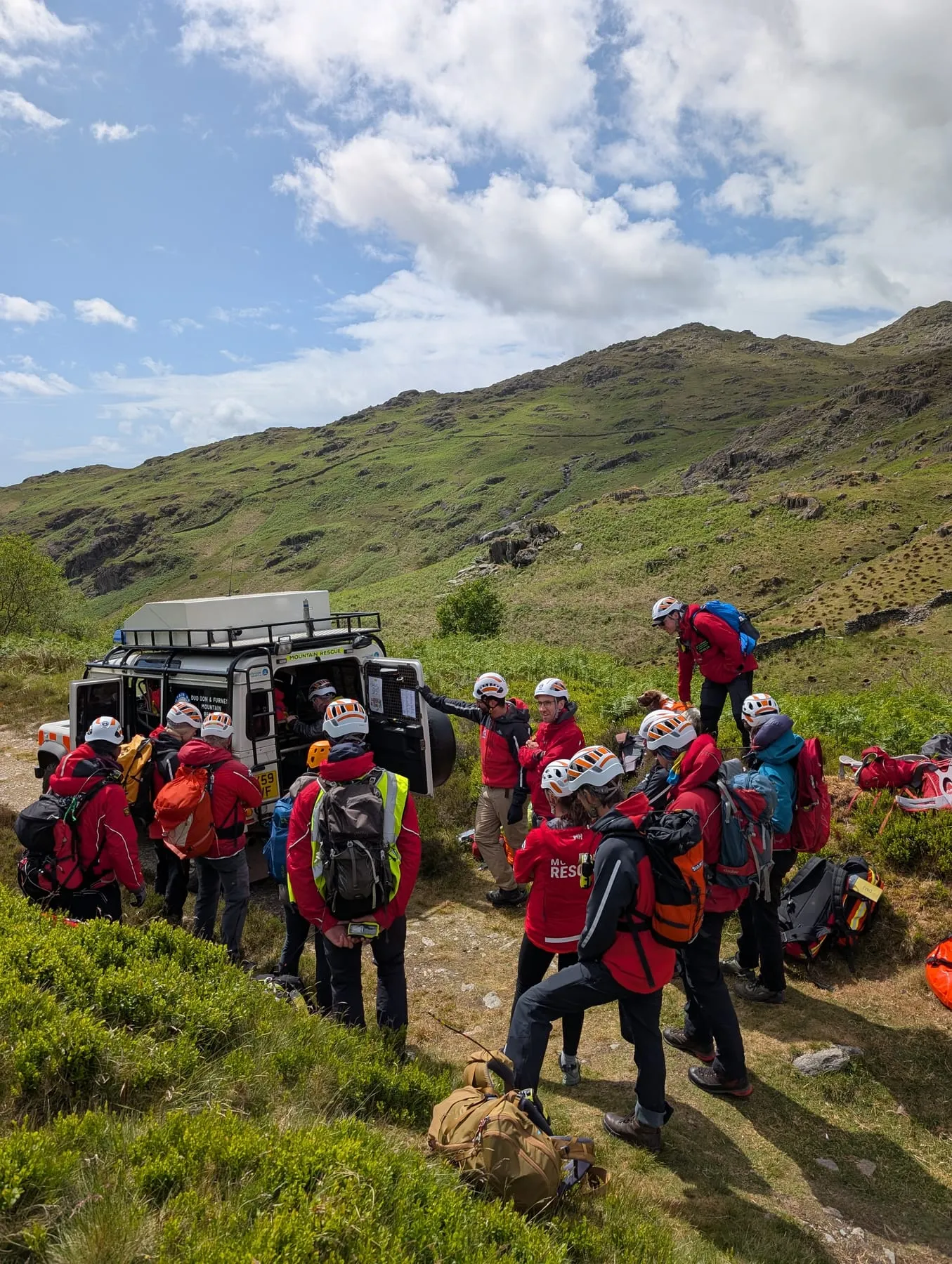 Team members gathered beside a Land Rover on a fellside