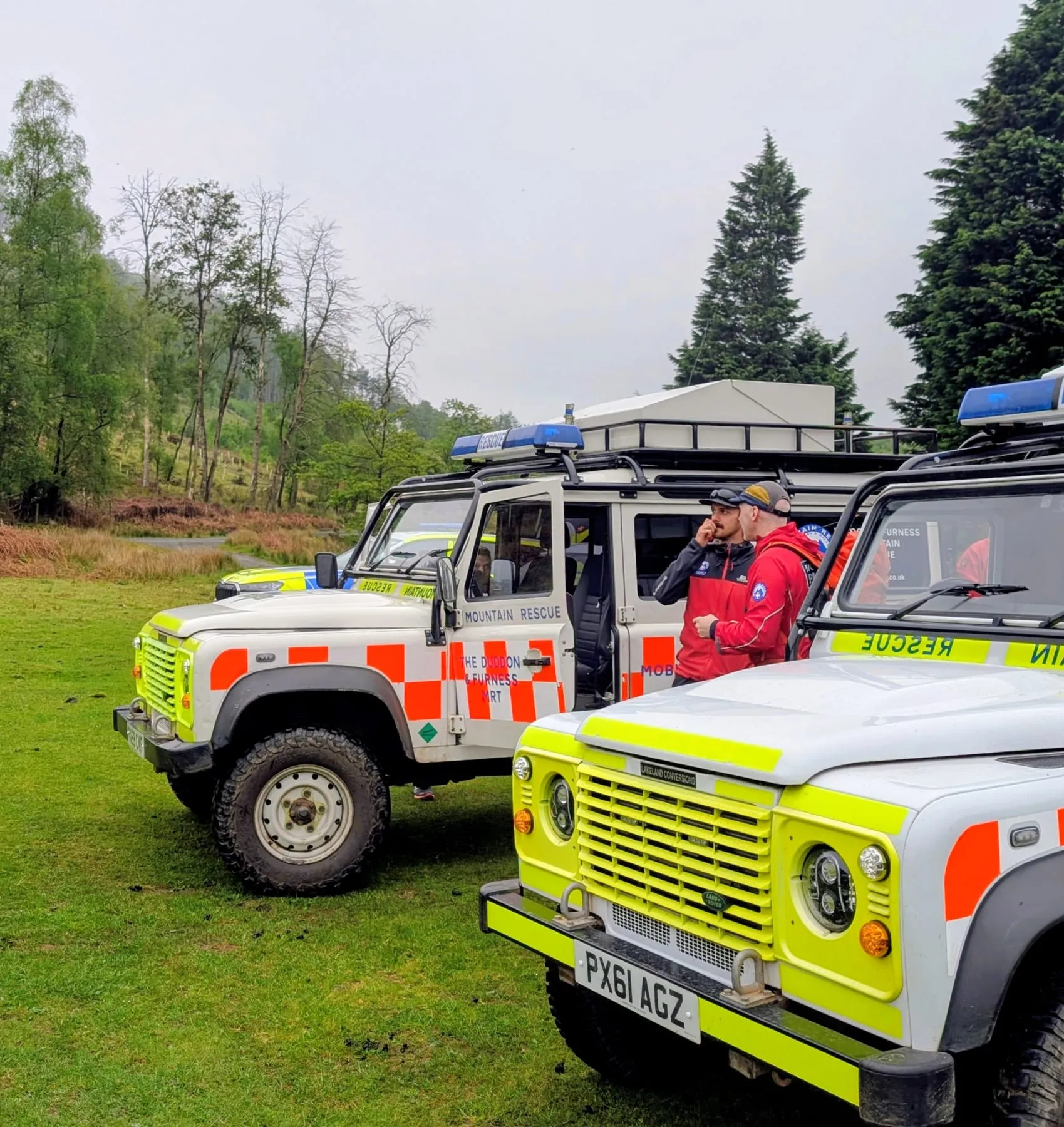 Two team Land Rovers parked on grass