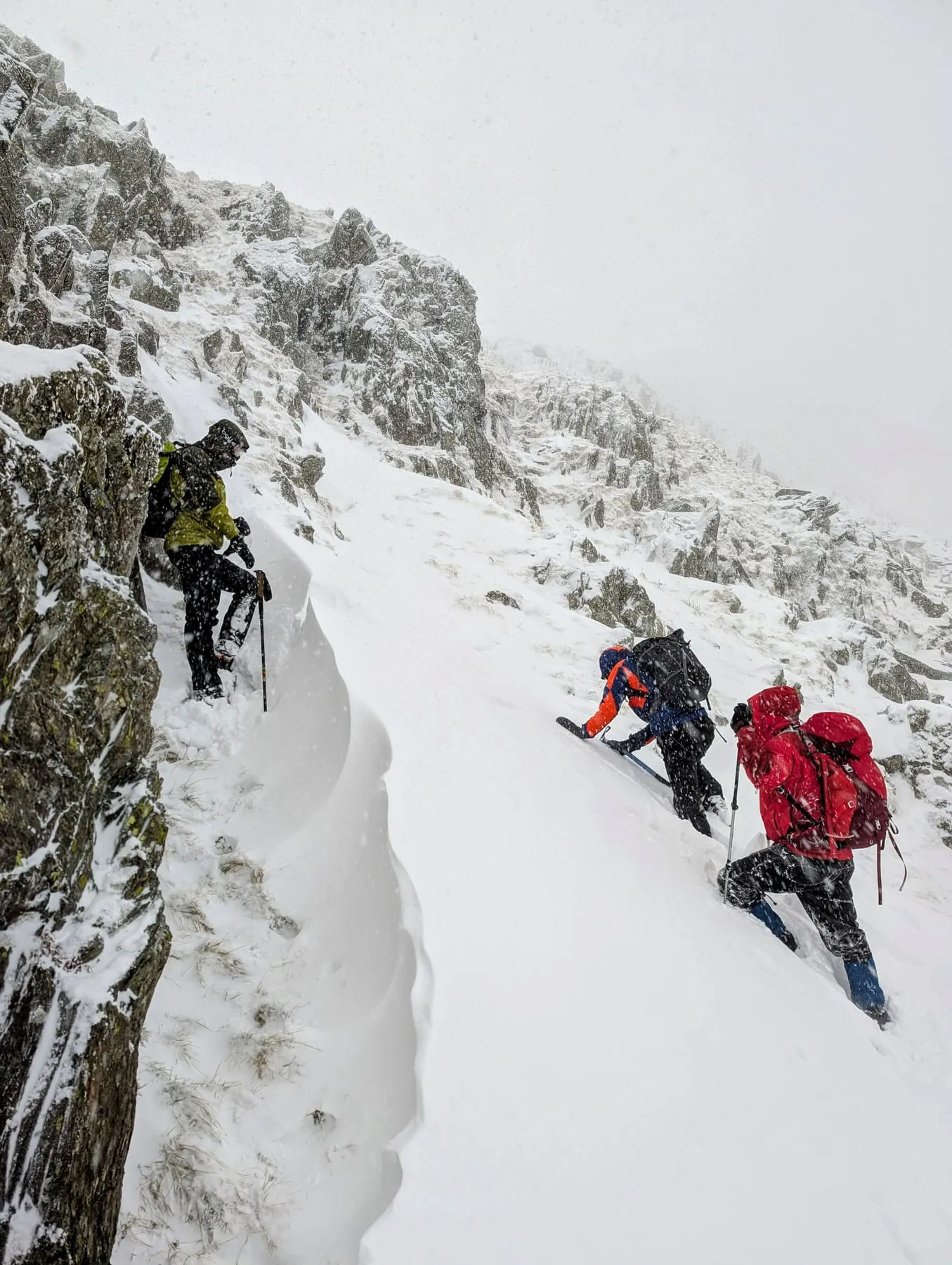 Three team members climbing a steep snow-covered gully